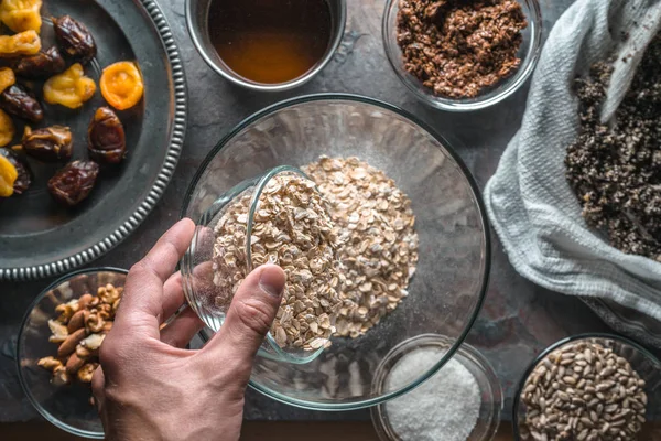 Hand met een kom van haver, ingrediënten voor muesli en een kom voor het mengen van close-up — Stockfoto