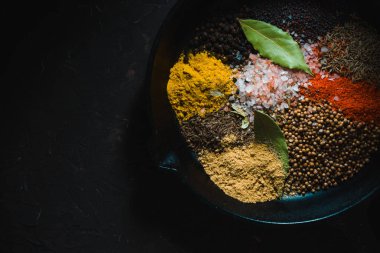 Koyu arka plan üzerine tavada farklı Hint baharat görüntülemek