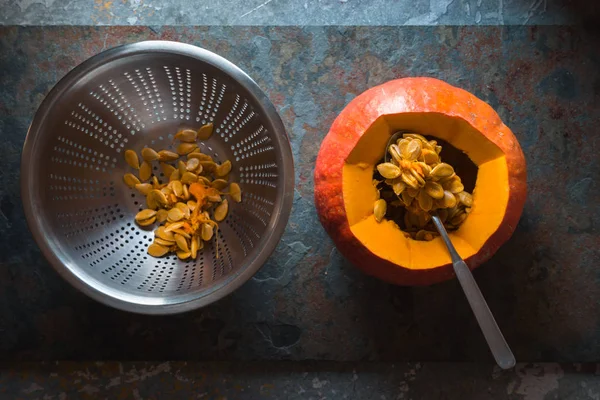 Sieb mit Samen, ein Löffel in Kürbis zum Kochen von Kürbissuppe — Stockfoto