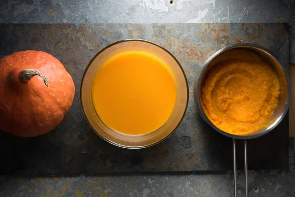 Pumpkin puree in a saucepan, pumpkin soup and pumpkin on a gray stone — Stock Photo, Image