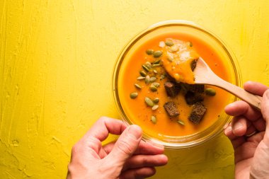 Tohum ve kruton sarı tablo ve elinde kaşık ile kabak çorbası