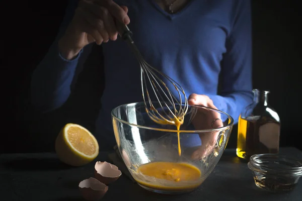 Gemas de ovo batidas em uma tigela de vidro com batedor, limão e azeite close-up — Fotografia de Stock