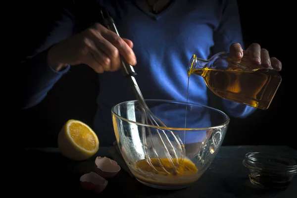 Оливковое масло наливают в взбитые желтки для приготовления майонеза — стоковое фото