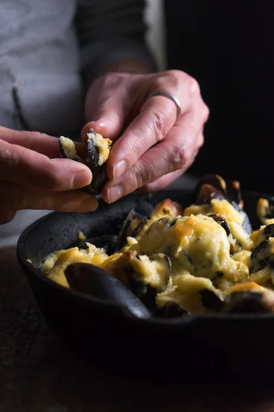 Female hands over a frying pan with mussels under cheese sauce — Stock Photo, Image
