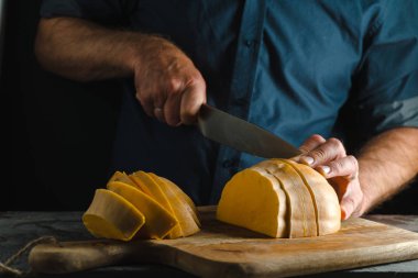 Mutfak bıçak yarım bir kabak bir ahşap tahta yakın çekim kesiyor.