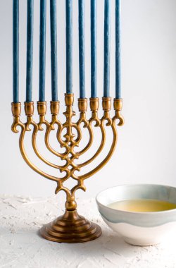 Mavi mum ve bir kase içinde tereyağı ile Hanukkah Menorah pirinç