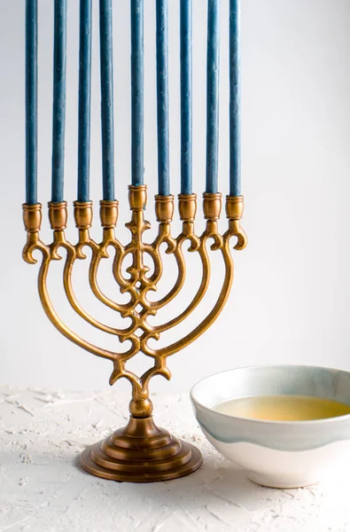 Menorah bronze Hanukkah com velas azuis e manteiga em uma tigela — Fotografia de Stock