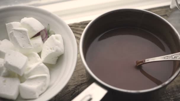 Зефир в керамической миске и какао в кастрюле на деревянном подставке — стоковое видео