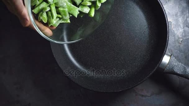 Laying the green beans from a bowl in a frying pan closeup — Stock Video