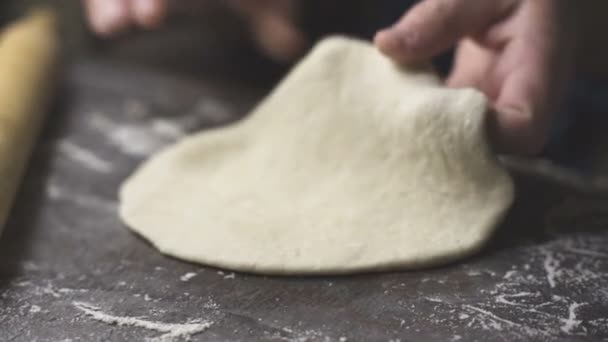 Rouler la pâte avec un rouleau en bois sur la table. Vidéo — Video