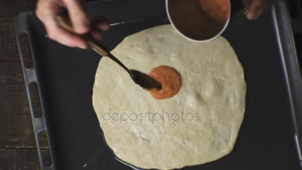 El agricultor extiende la pasta de tomate sobre la masa de pizza. Vídeo — Vídeo de stock