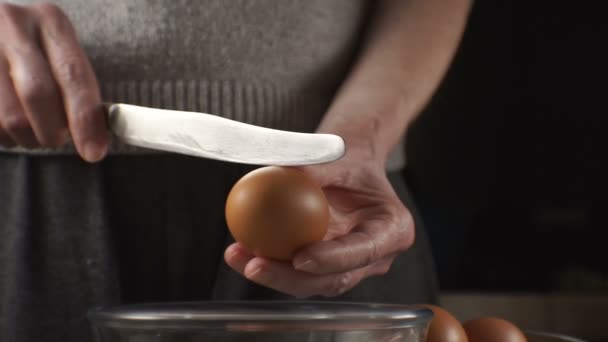 Τα χέρια με ένα μαχαίρι χτυπώντας ένα κέλυφος αυγού στον κάδο στην κουζίνα. Βίντεο — Αρχείο Βίντεο