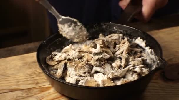 Mannen är att blanda i stekpannan champinjoner, vitlök och grädde. Video — Stockvideo