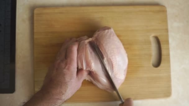 男はハーフで鶏の胸肉をカットします。 — ストック動画