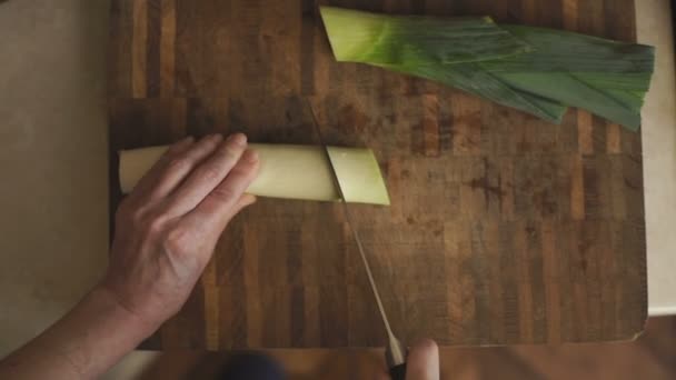 Woman is cutting a leek on a wooden board — Stock Video