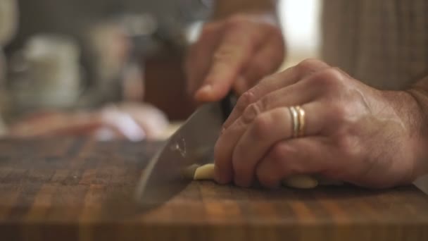 L'uomo sta tagliando l'aglio su una tavola di legno — Video Stock