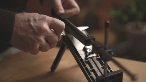 Ο άνθρωπος ακονίζει ένα μαχαίρι με ειδική ξύστρα για μαχαίρια βίντεο — Αρχείο Βίντεο