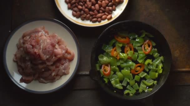 Pieces of chicken, beans. Pepper and chili in a frying pan view from above. Video — Stock Video