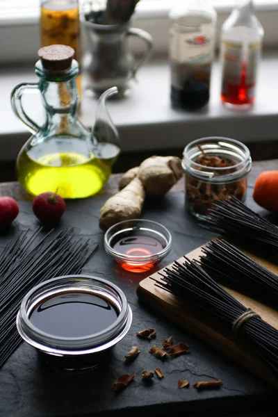 Vermicelli arroz preto e legumes na mesa, garrafas de vinagre no peitoril da janela. Cozinha asiática — Fotografia de Stock