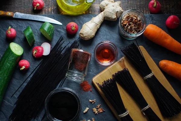 Vermicelli de arroz preto, vinagre e verduras em uma visão de ardósia preta de cima. Cozinha asiática — Fotografia de Stock