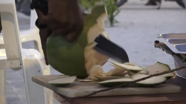 Man skär av bitar från en ung färsk kokosnöt. Maldiverna video — Stockvideo