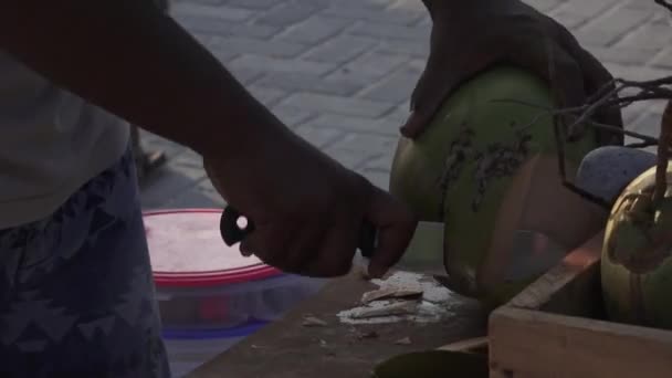Man skär av bitar från en ung färsk kokosnöt. Maldiverna video sidovy — Stockvideo