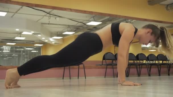 Chica en un traje deportivo hace estiramiento en el gimnasio — Vídeos de Stock