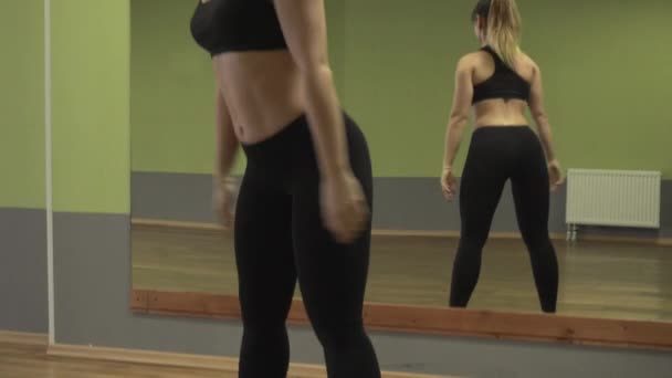 Ung aktiv flicka gör knäböj framför en spegel — Stockvideo