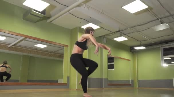 Joven chica activa realiza un elemento de danza delante de un espejo — Vídeo de stock