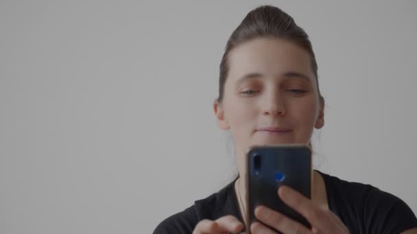 Close-up video of a young woman holding a mobile phone in her hands — Stock Video