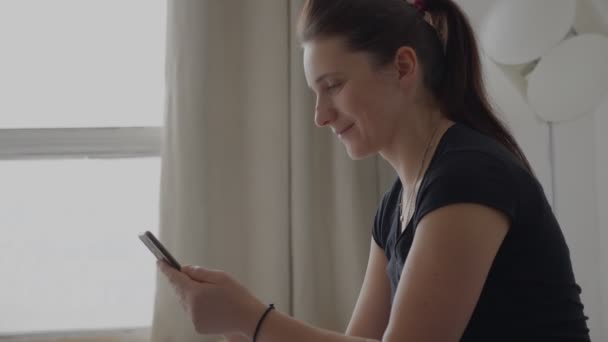 Jeune femme tenant un téléphone portable dans ses mains vue latérale — Video