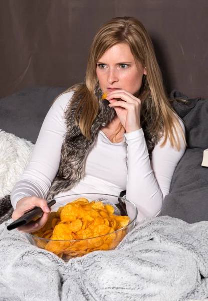 Привлекательная женщина ест чипсы и боится телевидения — стоковое фото