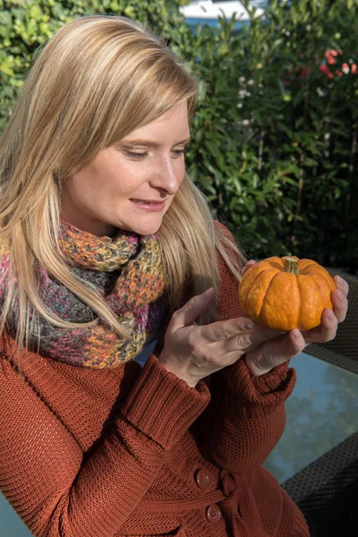 Aantrekkelijke blonde vrouw kussen pompoen in najaar — Stockfoto