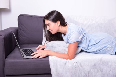 Genç çekici kadın kanepede yatan ve compu ile çalışma