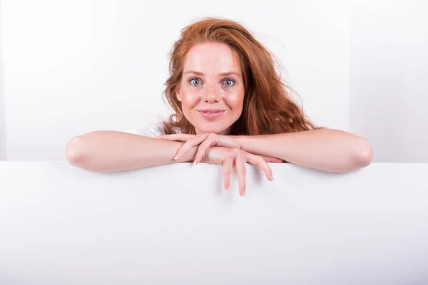 Beautiful red-haired woman holds a white board — Stock Photo, Image