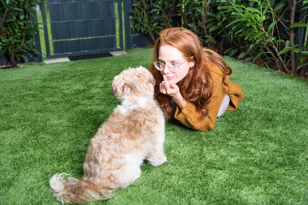 Schöne rothaarige Frau im Garten mit ihrem Hund — Stockfoto