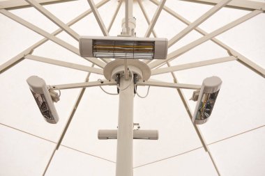 Serinlik e karşı bir şemsiye altında elektrikli radyatörler