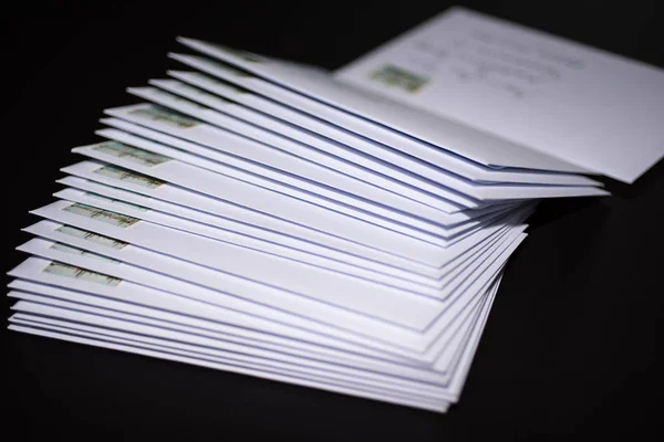 Franked harflerle siyah arka plan üzerine beyaz zarf yığını