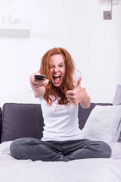 Beautiful, young, redheaded woman likes the TV program — Stock Photo, Image