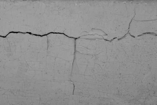 The old surface is covered with cracks and peeling paint and plaster.