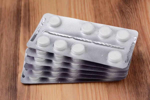 Pack of blisters with pills on a wooden surface, close-up