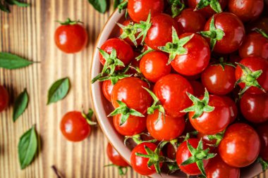 kiraz domates ve fesleğen ahşap arka plan üzerinde.