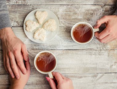 tea lovers ' hands. On wooden background. clipart