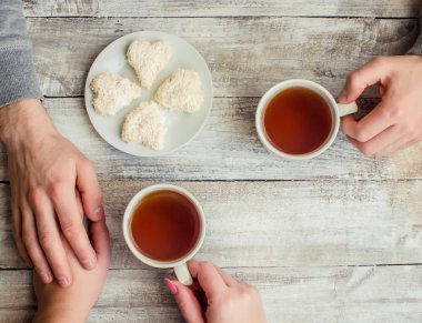 çay aşıkların eller. Ahşap arka plan üzerinde.