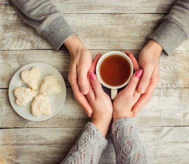 çay aşıkların eller. Ahşap arka plan üzerinde.