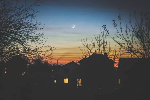 Вечерний дом в тени и молодой месяц . — стоковое фото