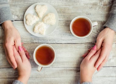 çay aşıkların eller. Ahşap arka plan üzerinde.