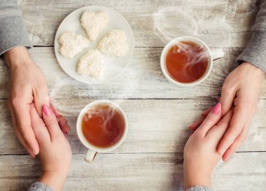 çay aşıkların eller. Ahşap arka plan üzerinde.