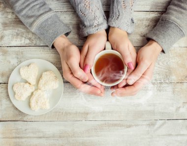 çay aşıkların eller. Ahşap arka plan üzerinde.