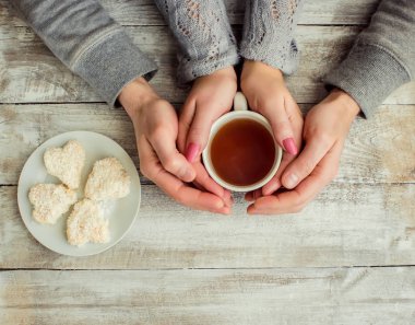 çay aşıkların eller. Ahşap arka plan üzerinde.